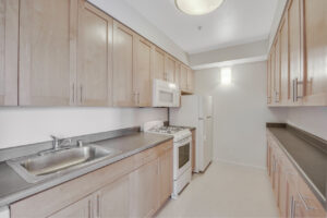 Interior Unit Kitchen, white appliances, white walls, light brown cabinetry, gray laminate countertops.