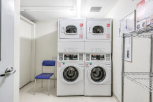 Interior Laundry Facilities, stacked washer and dryers., tile floor, blue chair.