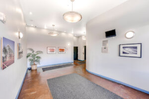 Interior Lobby, Concrete floors with gray carpeting, landscape art on walls,potted plant in corner.
